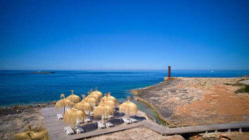 a group of chairs lined up on a pier near the water at Universal Hotel Romantica in Colonia Sant Jordi