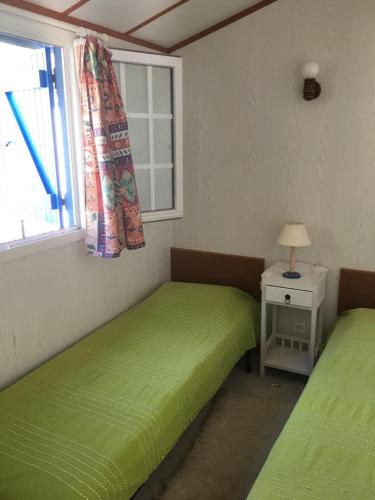 - 2 lits verts dans une chambre avec fenêtre dans l'établissement Wooden chalet, for 4 people air-conditioned, à Saint-Cyr-en-Talmondais