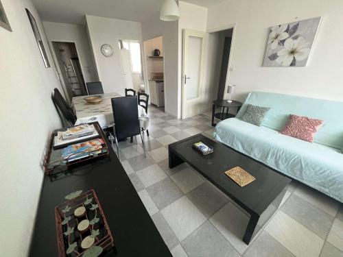 un salon avec un canapé bleu et une table dans l'établissement Charmant T3 en bord de mer, parking privé, animaux admis, non-fumeurs, proche commerces et pistes cyclables - FR-1-324A-59, à Saint-Hilaire-de-Riez