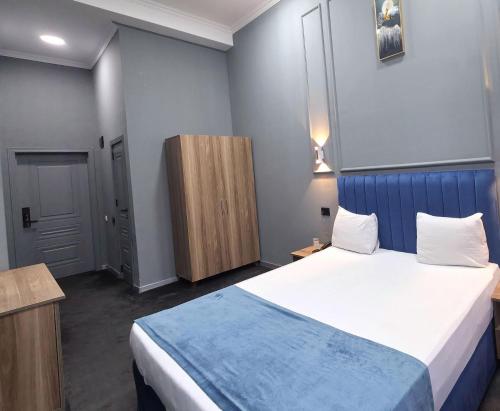 a bedroom with a large bed with a blue headboard at Will Hotel in Baku