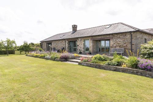 a stone house with a garden in front of it at East Lodge, Yorkshire in Bedale