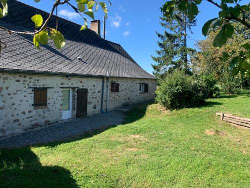 un vieux bâtiment en pierre avec une cour gazonnée dans l'établissement Gîte des Eperviers, à Étival