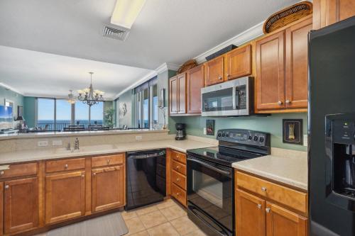 Emerald Dolphin Unit 1450 في شاطئ بينساكولا: مطبخ مع خزائن خشبية وفرن موقد