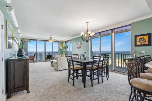 Emerald Dolphin Unit 1450 في شاطئ بينساكولا: غرفة طعام وغرفة معيشة مع طاولة وكراسي