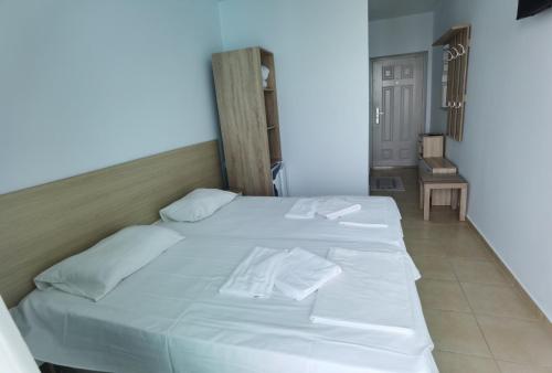 a large white bed with two white towels on it at хотел Ропотамо in Primorsko