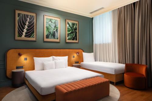 a hotel room with two beds and a chair at Verno House Budapest, Vignette Collection by IHG in Budapest