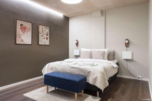a bedroom with a large bed and a blue stool at Modern Easy-Access 1BR Apartment in Midtown in Aarhus