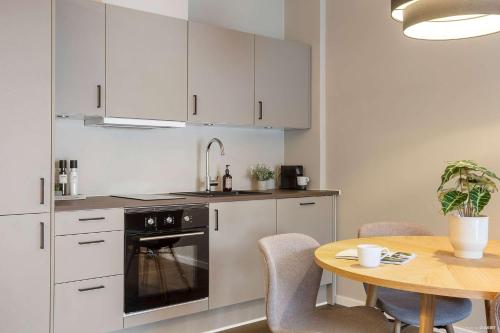 a kitchen with white cabinets and a table with chairs at Modern Easy-Access 1BR Apartment in Midtown in Aarhus