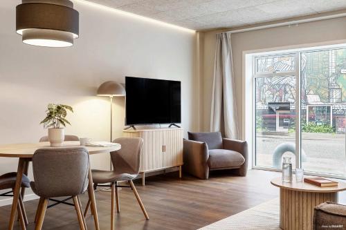 a living room with a tv and a table and chairs at Modern Easy-Access 1BR Apartment in Midtown in Aarhus