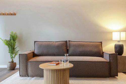 a brown couch in a living room with a table at Modern Easy-Access 1BR Apartment in Midtown in Aarhus