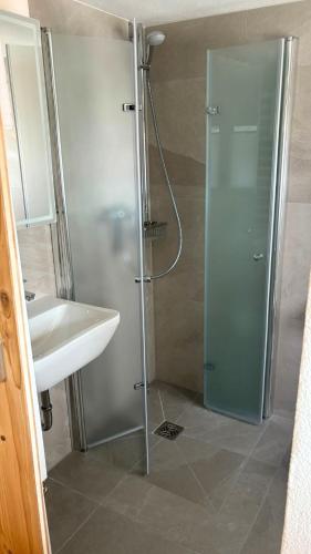 a shower with a glass door next to a sink at Haus Heimatfrieden Mittenwald in Mittenwald