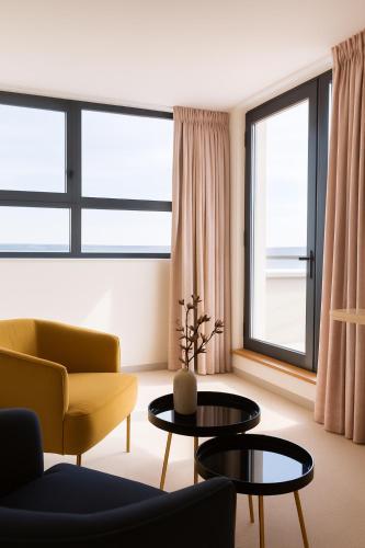 a living room with a yellow chair and a table at Le Nautica Hôtel in Perros-Guirec