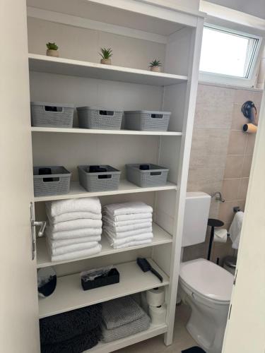 a bathroom with a shelf with towels and a toilet at Chill & Relax Ferienhaus Breitenbrunn in Breitenbrunn