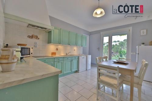 une cuisine avec des placards verts et une table avec des chaises dans l'établissement Le Rocher, à Carry-le-Rouet