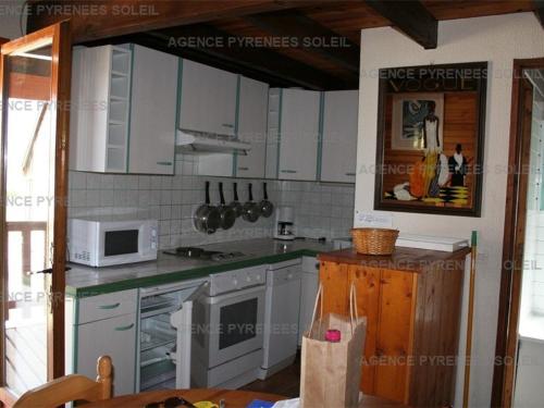 une cuisine avec des armoires blanches et un micro-ondes dans l'établissement Chalet 3 chambres avec terrasse aux Angles - FR-1-295-145, aux Angles