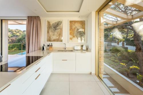une cuisine avec des placards blancs et une grande fenêtre dans l'établissement Villa Sous le Soleil, à Saint-Tropez