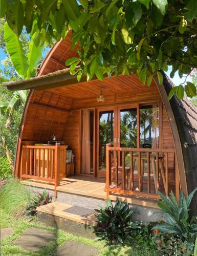a small wooden house with a porch in a garden at Sugita Wooden House 2 in Payangan