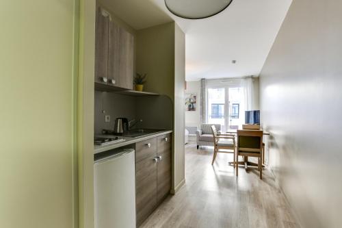 a kitchen with a table and a dining room at Zenitude Hôtel-Résidences Le Havre Les Docks in Le Havre