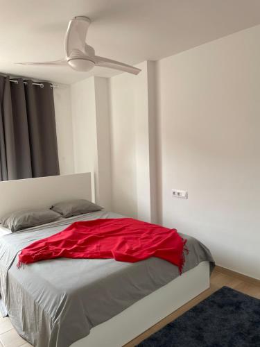 a bedroom with a bed with red sheets and a ceiling fan at Little Rose apartment in Godella