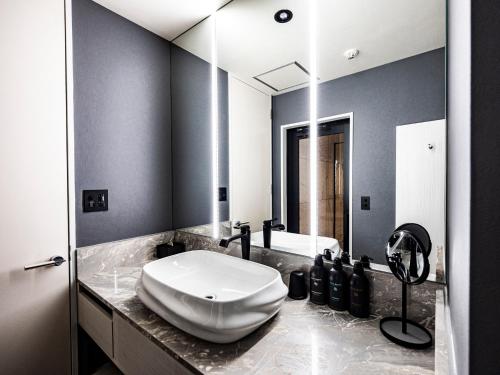 a bathroom with a white sink and a mirror at 十二ホテル -福岡空港- in Fukuoka