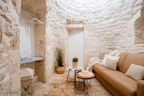 Una sala de estar con un sofá y una pared de piedra. en Trulli in Contrada - Monopoli, en Monopoli
