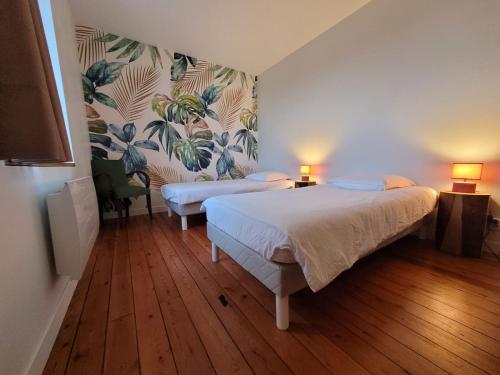 une chambre avec deux lits et un mur floral dans l'établissement Domaine Les Chauveaux, 3 gites, 26 personnes, 1 salle, à Antran