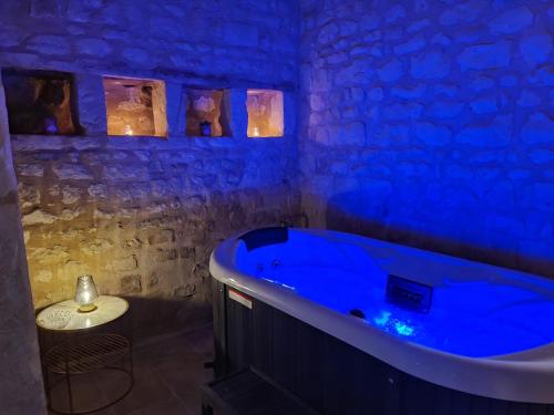 une baignoire bleue dans une pièce avec un mur en pierre dans l'établissement Domaine Les Chauveaux, 3 gites, 26 personnes, 1 salle, à Antran
