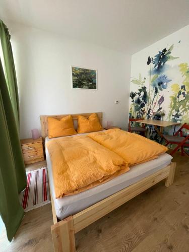 a bedroom with a bed with an orange comforter at Csomópont Családi Vendégház in Somogytúr