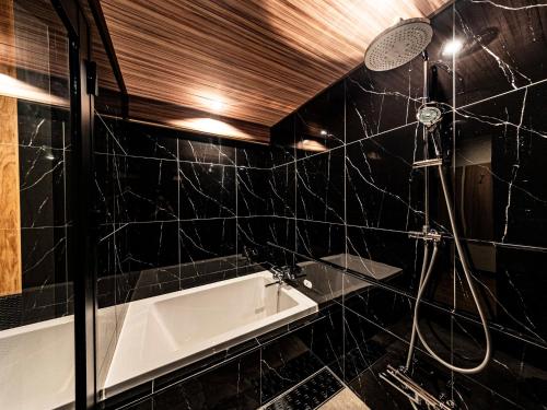 a black tiled bathroom with a shower and a tub at 十二ホテル -福岡空港- in Fukuoka