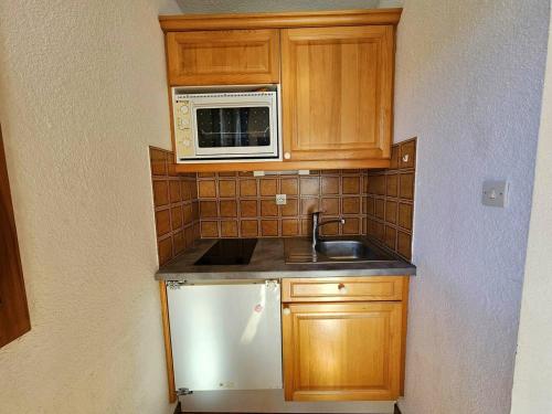 une petite cuisine avec un évier et un micro-ondes dans l'établissement Plan Peisey: Appartement 2 pièces 5 pers, accès pistes, animaux admis - FR-1-757-109, à Peisey-Nancroix