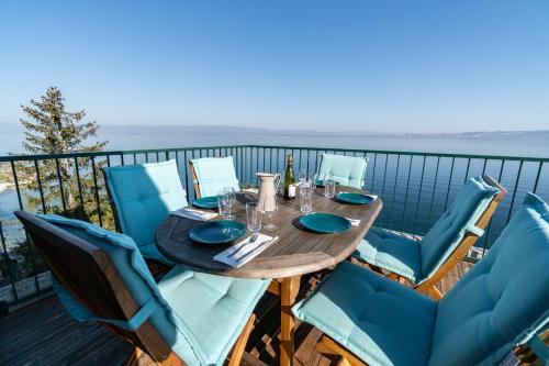 une table et des chaises sur un balcon avec vue sur l'eau dans l'établissement La Villa du Lac - Appartements de vacances - Les pieds dans l'eau, à Maxilly-sur-Léman