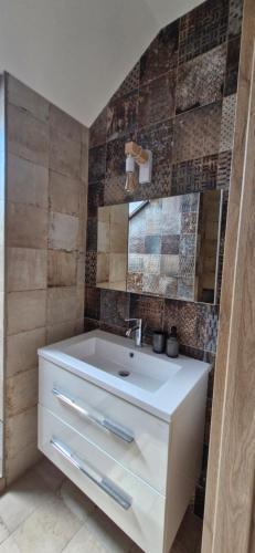a bathroom with a white sink and some tiles at Kapitány MP Art Luxury Apartman in Balatonboglár