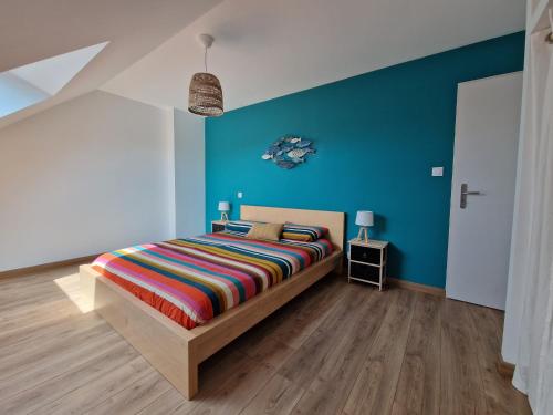 une chambre avec un lit et un mur bleu dans l'établissement Maison moderne pour 8 pers. à 600m de la plage avec grand jardin - FR-1-639-140, à Sarzeau