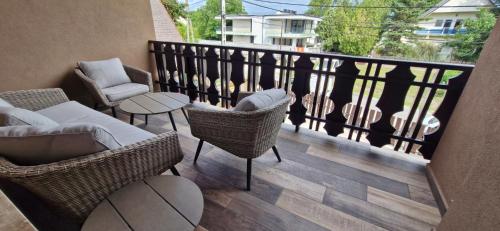 a balcony with wicker chairs and tables and a railing at Kapitány MP Art Luxury Apartman in Balatonboglár