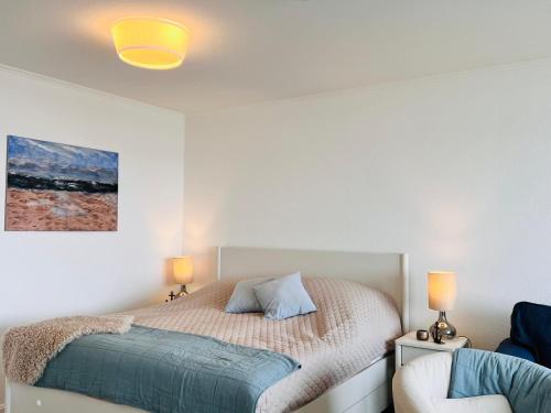 a bedroom with a bed and two lamps and a chair at Baltic Sea View in Fehmarn