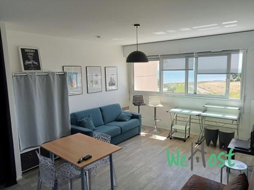 un salon avec un canapé bleu et une table dans l'établissement Alfred - Studio - Seafront - Parking, à La Rochelle