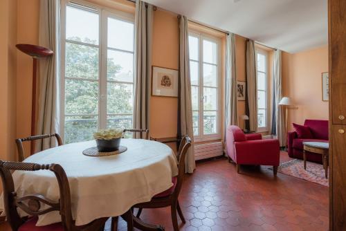 un salon avec une table, des chaises et des fenêtres dans l'établissement Veeve - Le Marais Retreat, à Paris