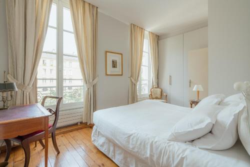 une chambre blanche avec un lit et un bureau dans l'établissement Veeve - Le Marais Retreat, à Paris