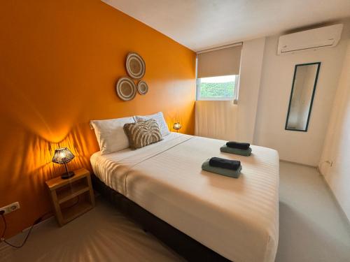 a bedroom with a large bed with an orange wall at Boutique Hotel & apartments JT Curaçao in Willemstad