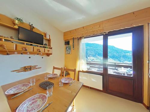 une salle à manger avec une table et une grande fenêtre dans l'établissement Studio ensoleillé avec balcon Sud, parking, navette, 4 couchages - Le Grand-Bornand - FR-1-241-98, au Grand-Bornand