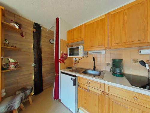 Elle comprend une petite cuisine avec des placards en bois et un évier. dans l'établissement Studio 4 Pers. avec Balcon Sud, Parking et Navette - Le Grand-Bornand - FR-1-241-221, au Grand-Bornand