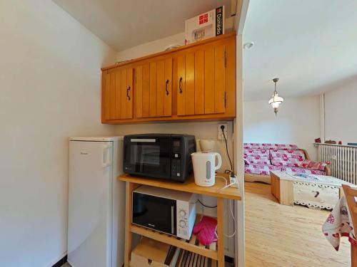 une petite cuisine avec un micro-ondes et un réfrigérateur dans l'établissement Charmant 2 pièces, 6 couchages, centre du Grand-Bornand, parking, balcon sud - FR-1-241-136, au Grand-Bornand