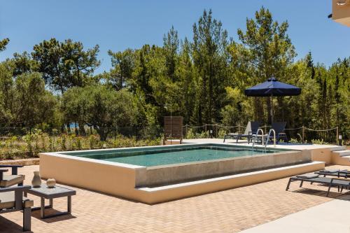 a pool in a patio with an umbrella and chairs at SOUND OF SEA Villas in Lixouri