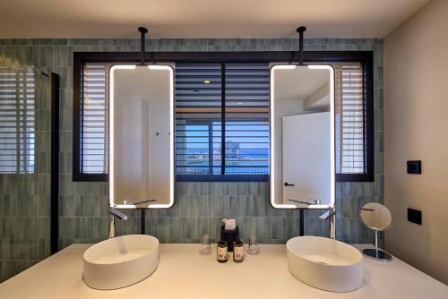 a bathroom with two sinks and two mirrors at Universal Hotel Romantica in Colonia Sant Jordi