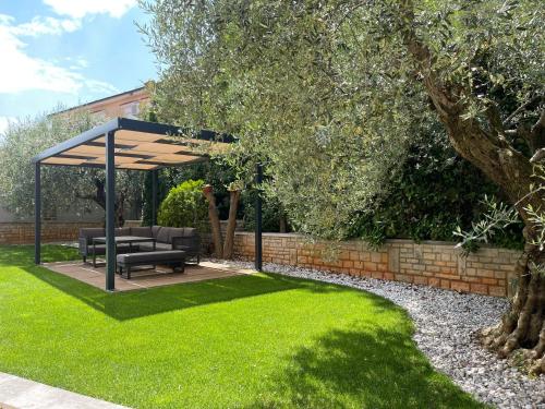 a garden with a pergola and a bench and grass at Apartmani Žužić in Poreč