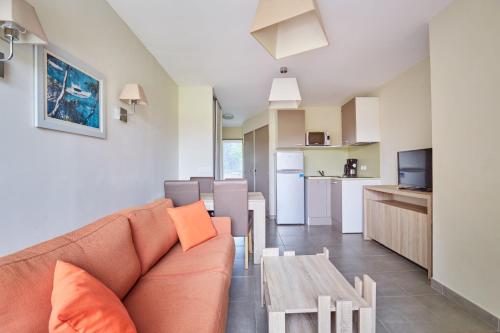 a living room and kitchen with a couch and a table at Résidence Odalys Côté Canal in Sallèles-dʼAude