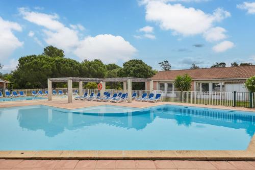 a swimming pool with blue lounge chairs at Résidence Odalys Côté Canal in Sallèles-dʼAude