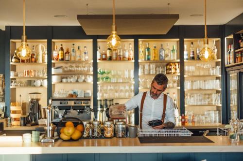 a man standing behind a counter in a kitchen at Beach Hotel - Le Grand Chalet in Ronce-les-Bains