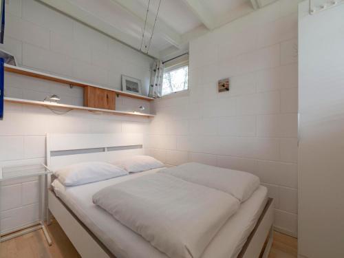 a bed in a room with white walls at Holiday Home near Sint Maartenszee Beach in Sint Maartensvlotbrug