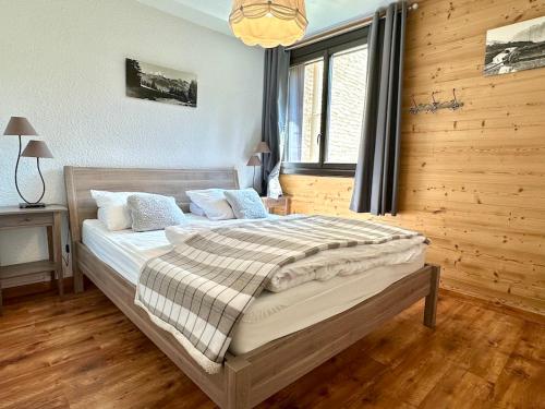 une chambre avec un grand lit dans une pièce en bois dans l'établissement FLOCON Joséphine Immobilier, à La Salle Les Alpes